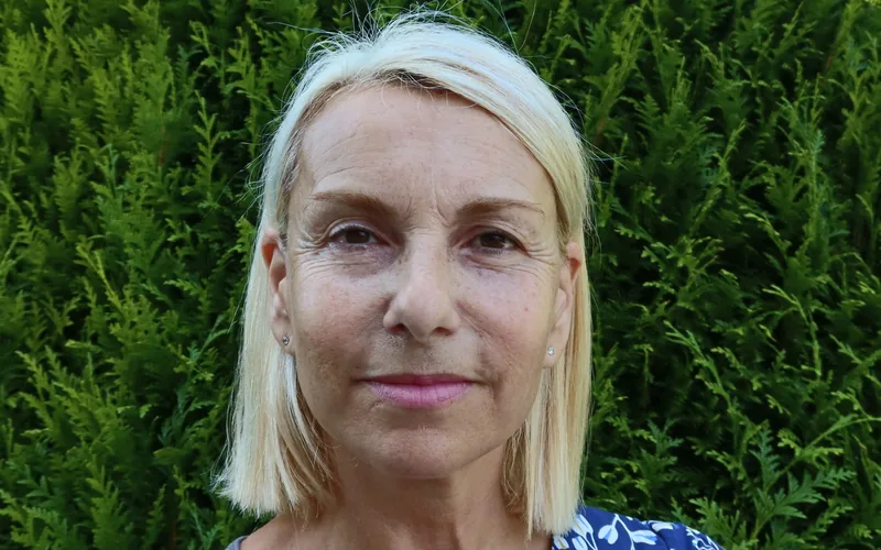 Rosalba Meslier, psychopraticienne et sophrologue, devant une haie de son jardin